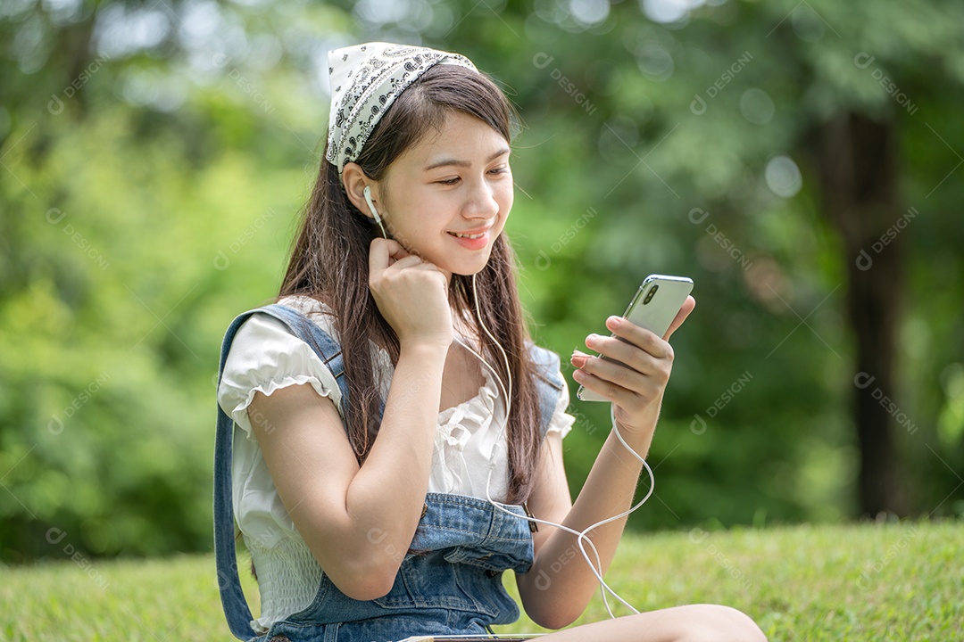 Retrato de menina com fones de ouvido fazendo gestos no parque verde da cidade verde em spri