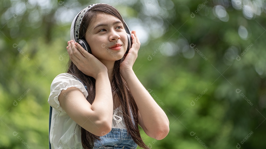 Retrato de menina com fones de ouvido fazendo gestos no parque verde da cidade verde em spri