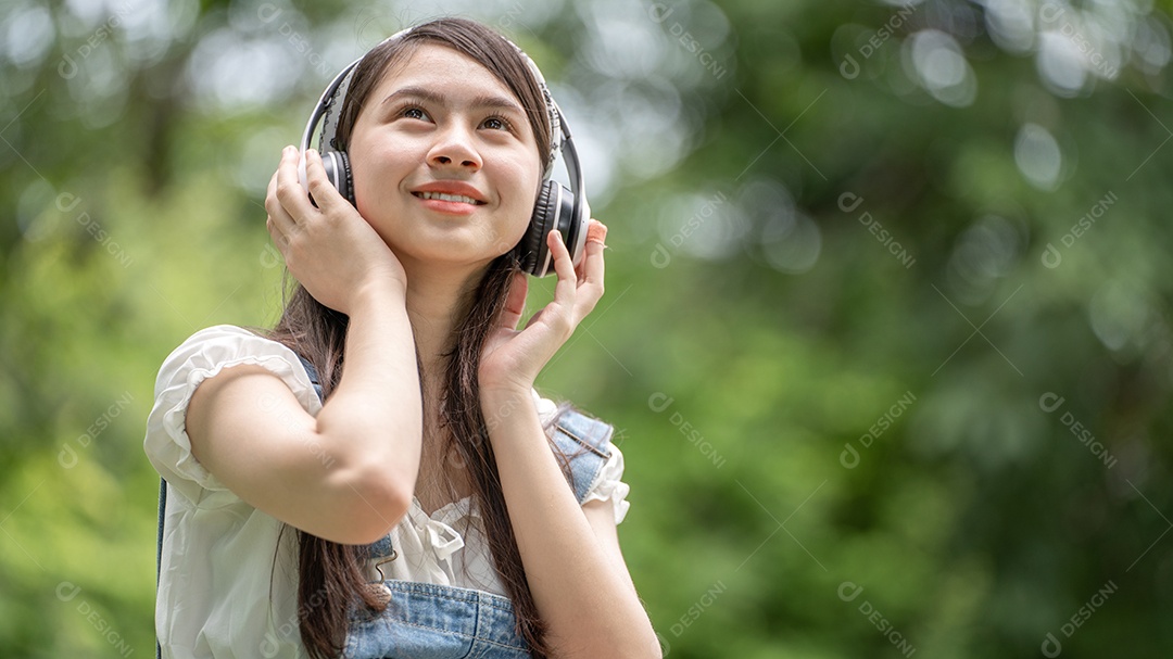 Retrato de menina com fones de ouvido fazendo gestos no parque verde da cidade verde em spri