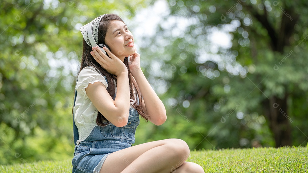 Retrato de menina com fones de ouvido fazendo gestos no parque verde da cidade verde em spri