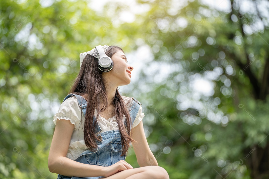 Retrato de menina com fones de ouvido fazendo gestos no parque verde da cidade verde em spri