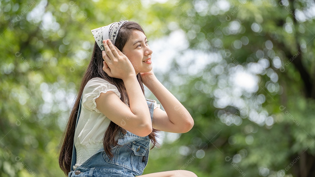 Retrato de menina com fones de ouvido fazendo gestos no parque verde da cidade verde em spri