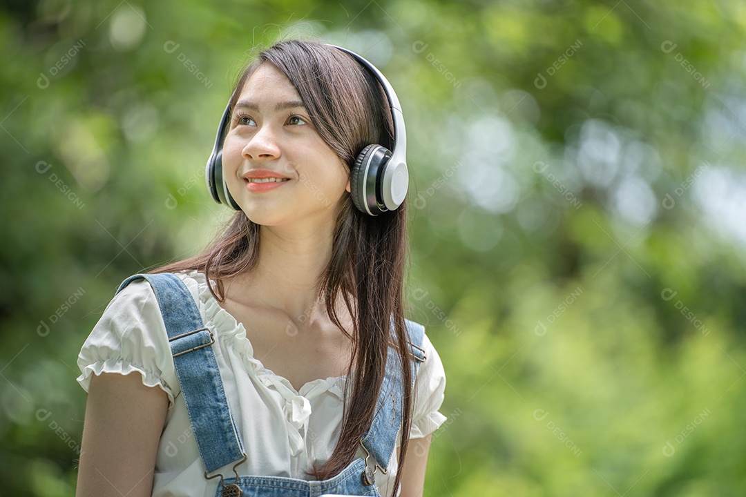 Portrait of girl with headphones making gestures in green city park in spri