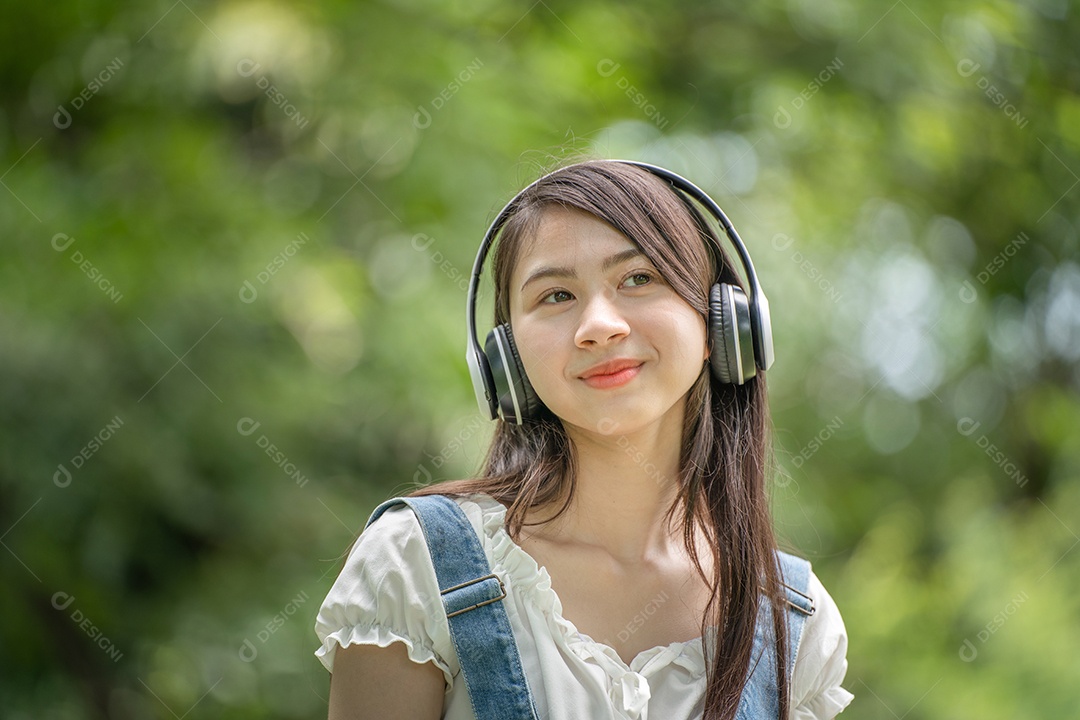 Retrato de menina com fones de ouvido fazendo gestos no parque verde da cidade verde em spri