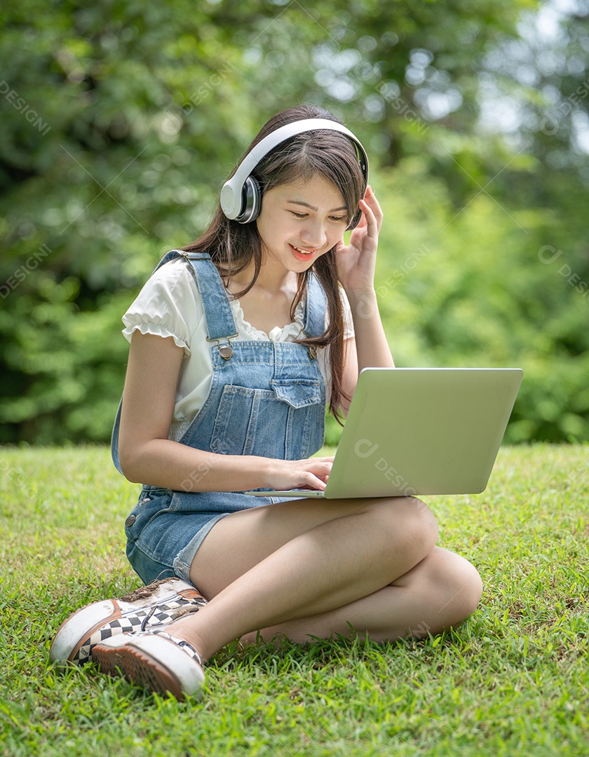 Retrato de menina com fones de ouvido e mexendo em notebook fazendo gestos no parque verde da cidade verde em spri