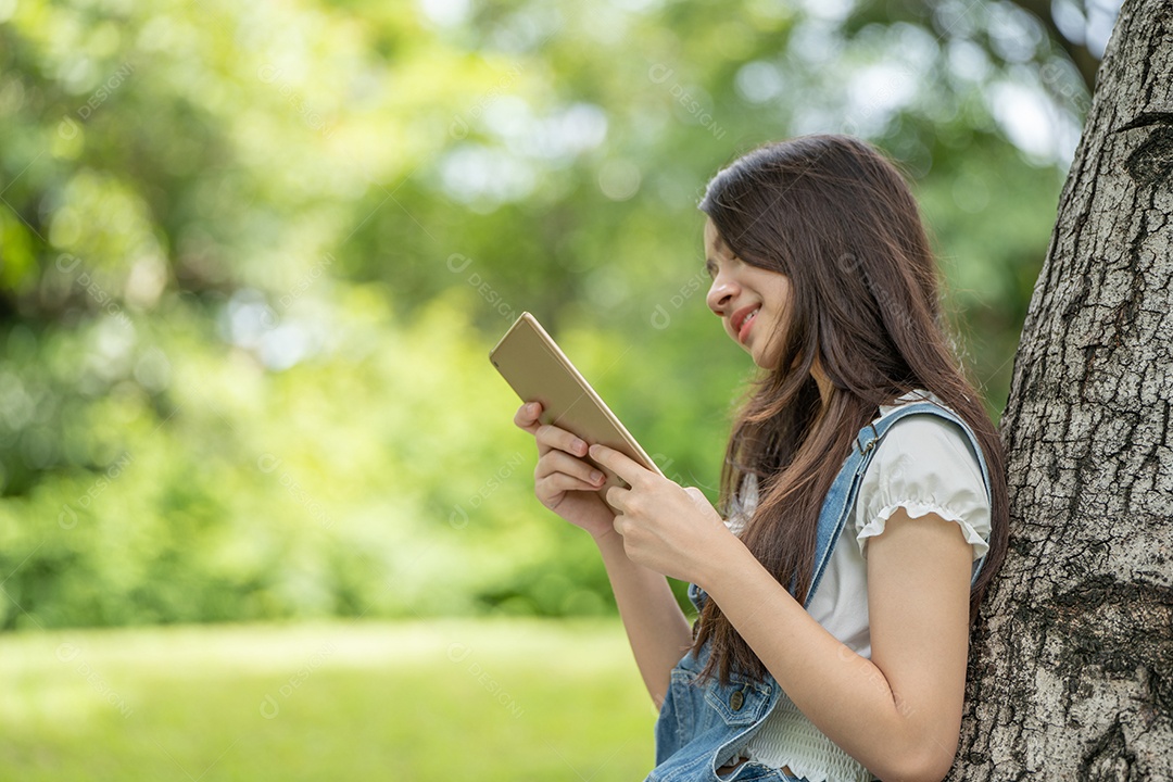 Retrato de menina segurando tablet fazendo gestos no parque verde da cidade verde em spri