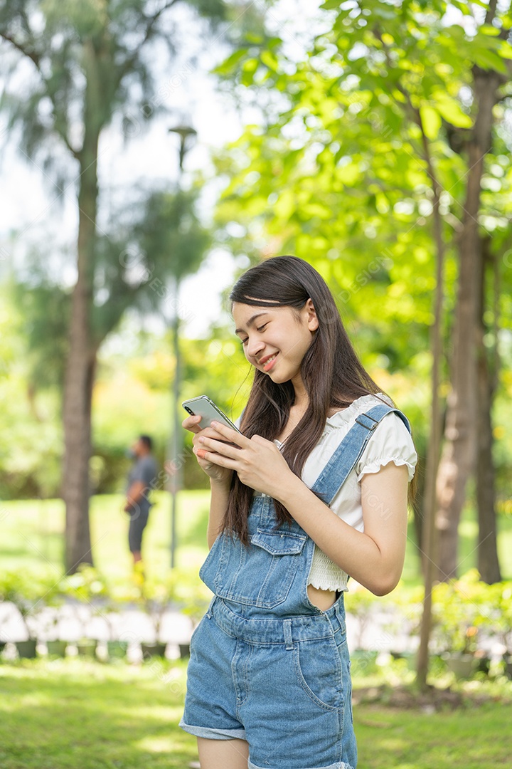 Retrato de menina mexendo no celular fazendo gestos no parque verde da cidade verde em spri