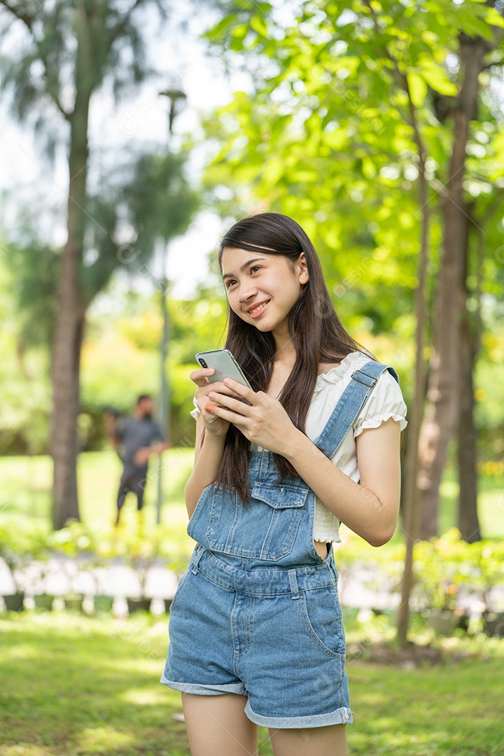 Retrato de menina mexendo no celular fazendo gestos no parque verde da cidade verde em spri