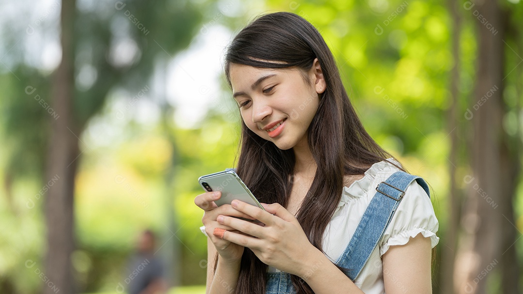 Retrato de menina mexendo no celular fazendo gestos no parque verde da cidade verde em spri