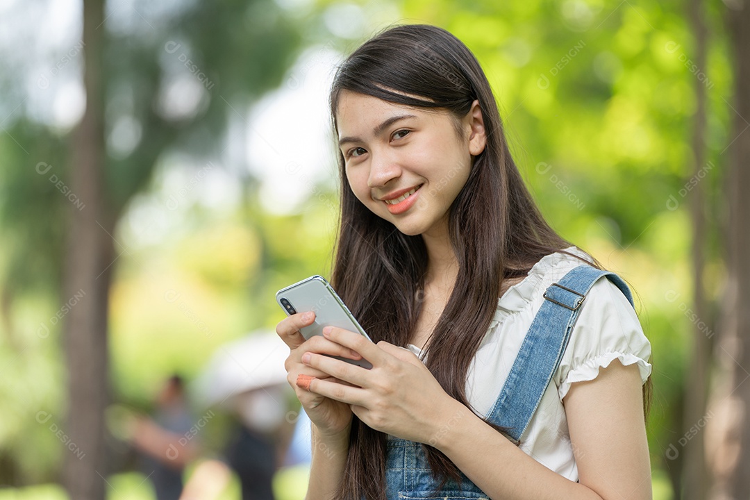 Retrato de menina mexendo no celular fazendo gestos no parque verde da cidade verde em spri