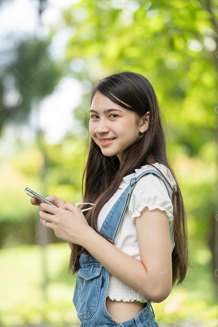 Retrato de menina mexendo no celular fazendo gestos no parque verde da cidade verde em spri