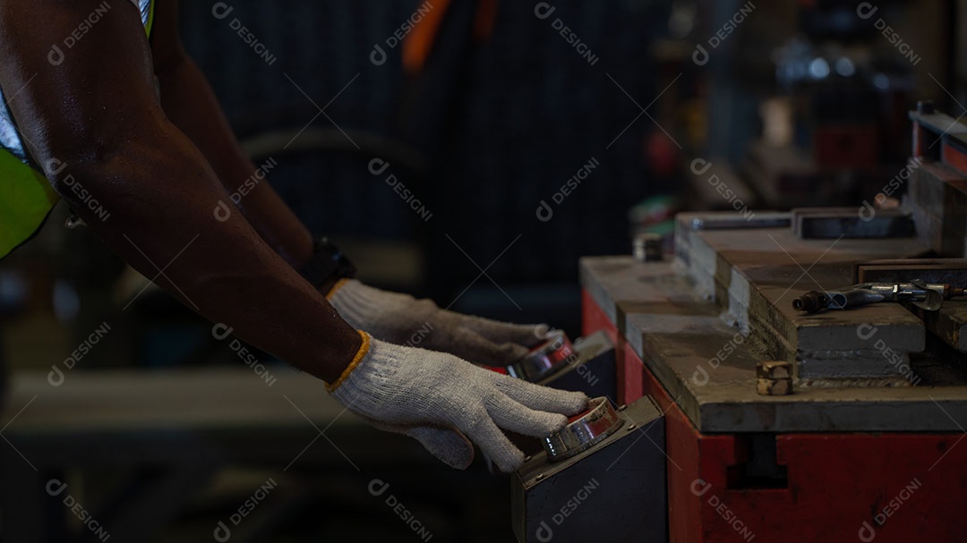 Afro-americano com luvas acionando botões de maquina, equipamento de segurança
