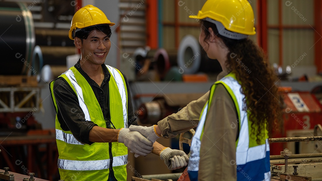 Capataz e mulher em traje de segurança apertam as mãos e concluem um trabalho