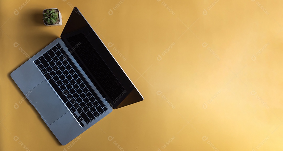 Computador portátil e cacto em fundo amarelo. Vista superior cópia espaço em branco.