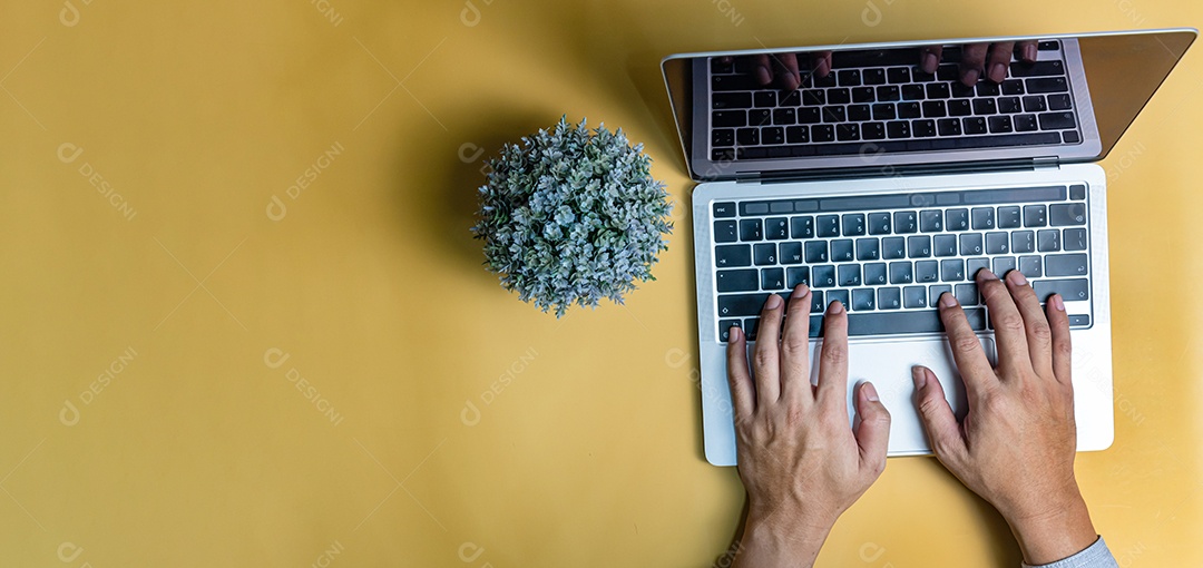 Homem usando laptop de computador teclado em fundo amarelo.