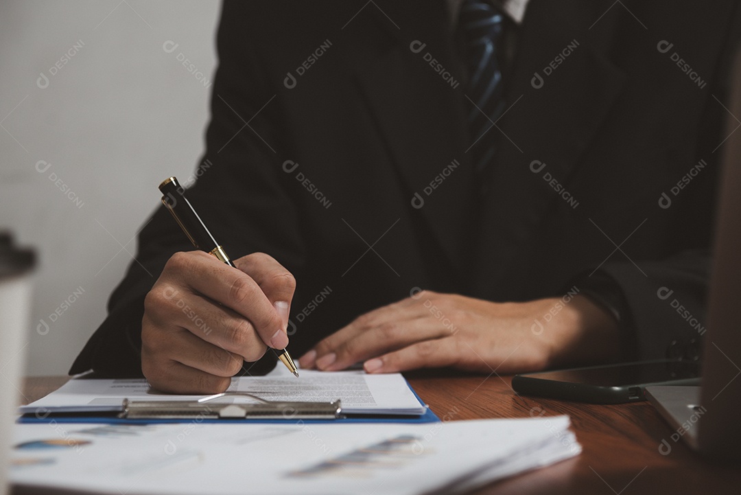 Empresário segurando o documento de assinatura de caneta na área de transferência na mesa.