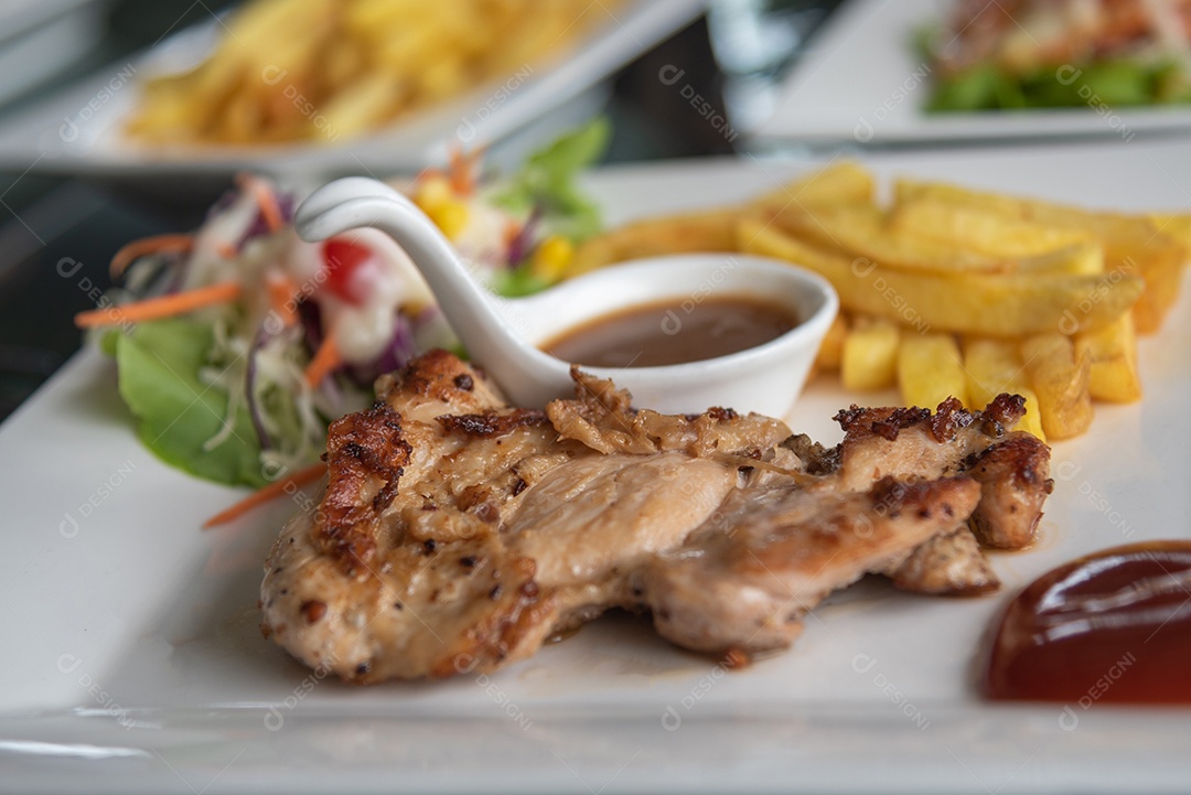 Bife de frango e salada de legumes no prato na mesa.