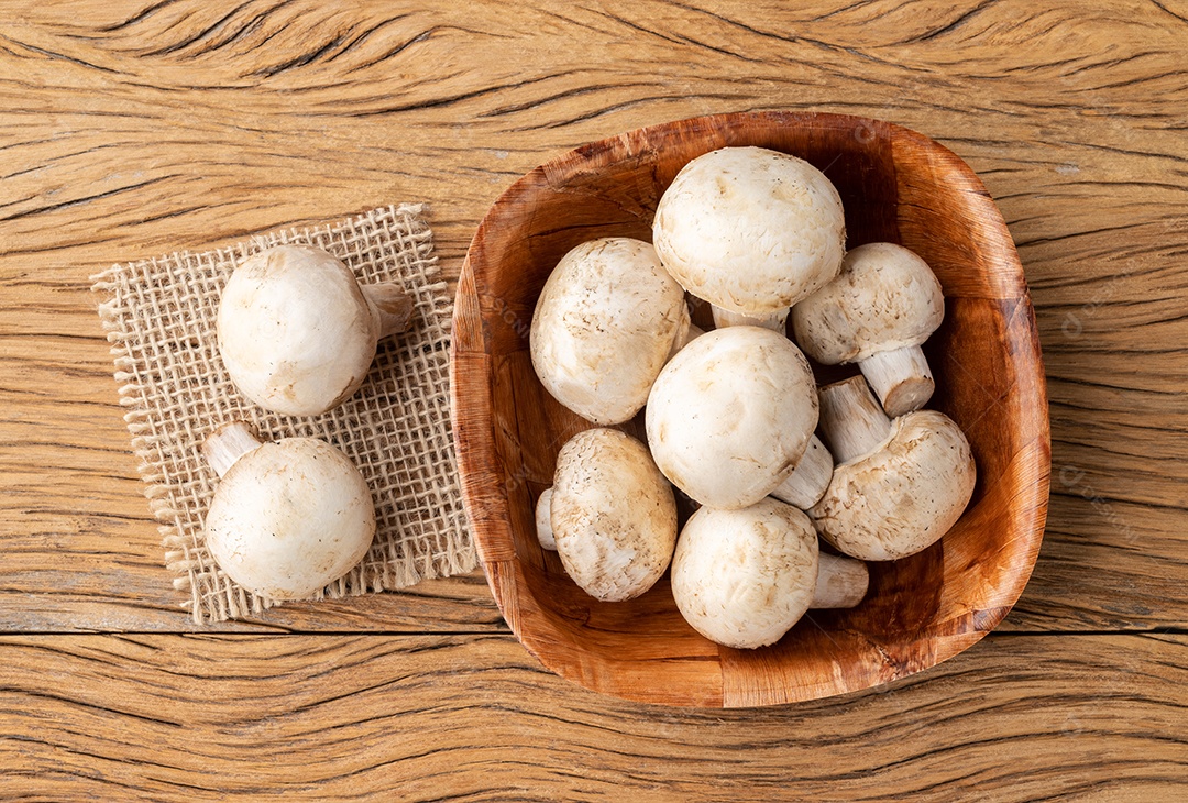 Cogumelos de Paris em uma tigela sobre a mesa de madeira.