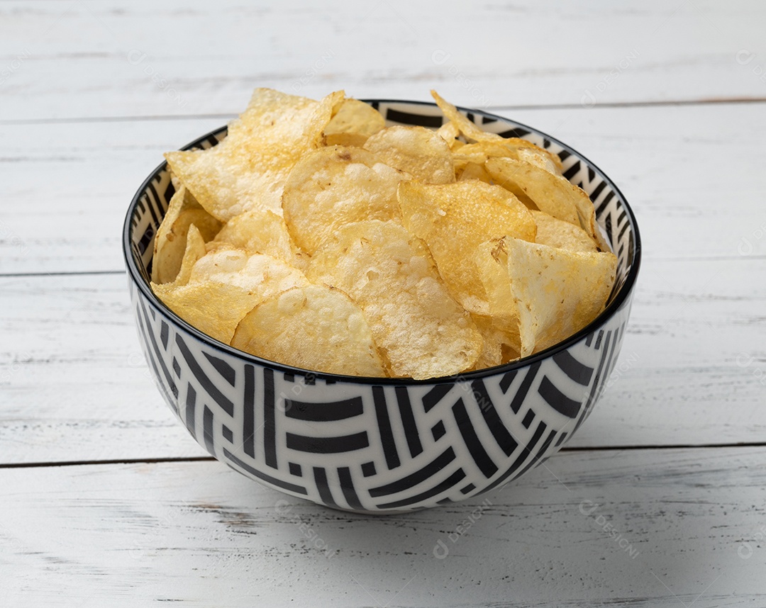 Batatas fritas em uma tigela sobre a mesa de madeira.