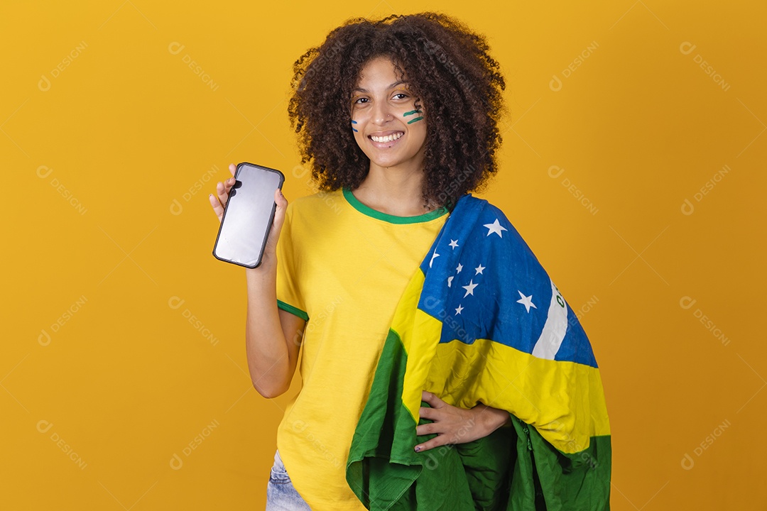 Mulher afro-brasileira vestindo camiseta do Brasil e segurando um smartphone celular