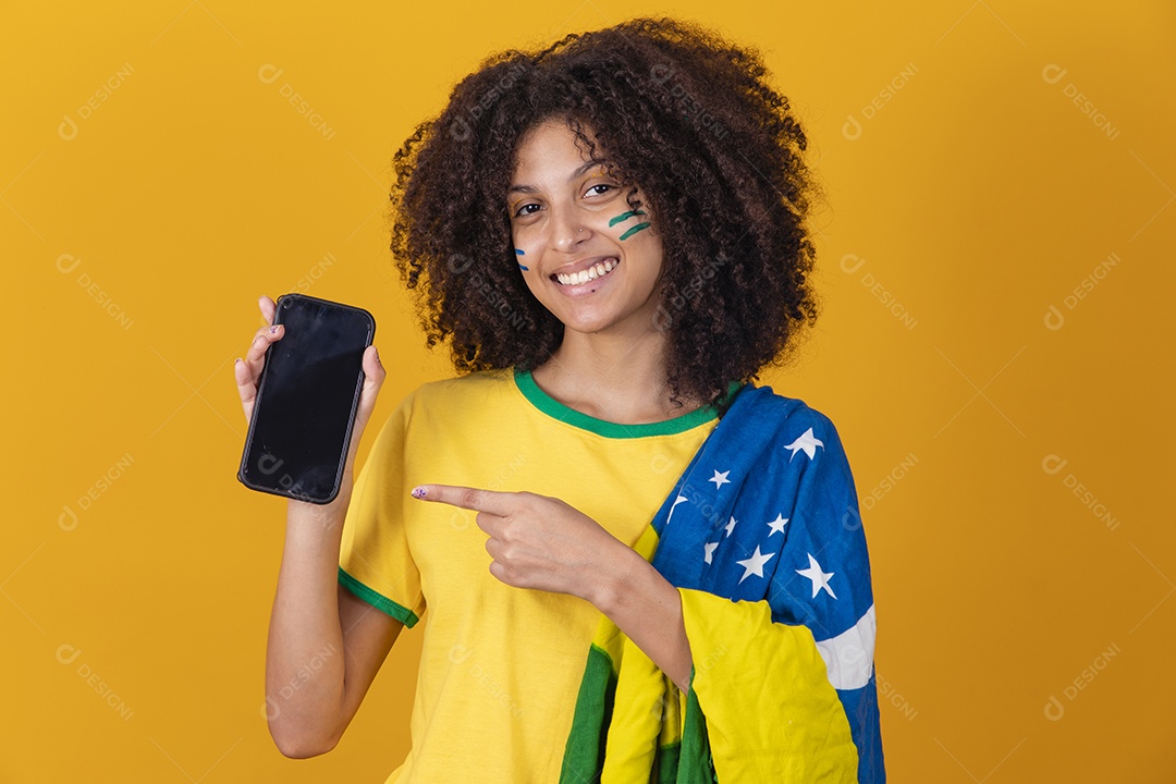 Mulher afro-brasileira vestindo camiseta do Brasil e segurando um smartphone celular