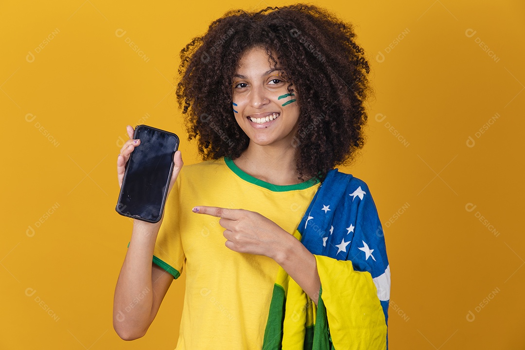 Mulher afro-brasileira vestindo camiseta do Brasil e segurando um smartphone celular