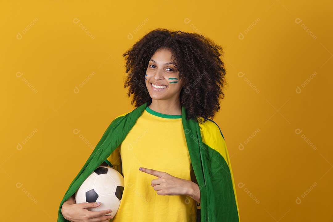 Mulher afro-brasileira vestindo camiseta do Brasil e segurando uma bola de futebol