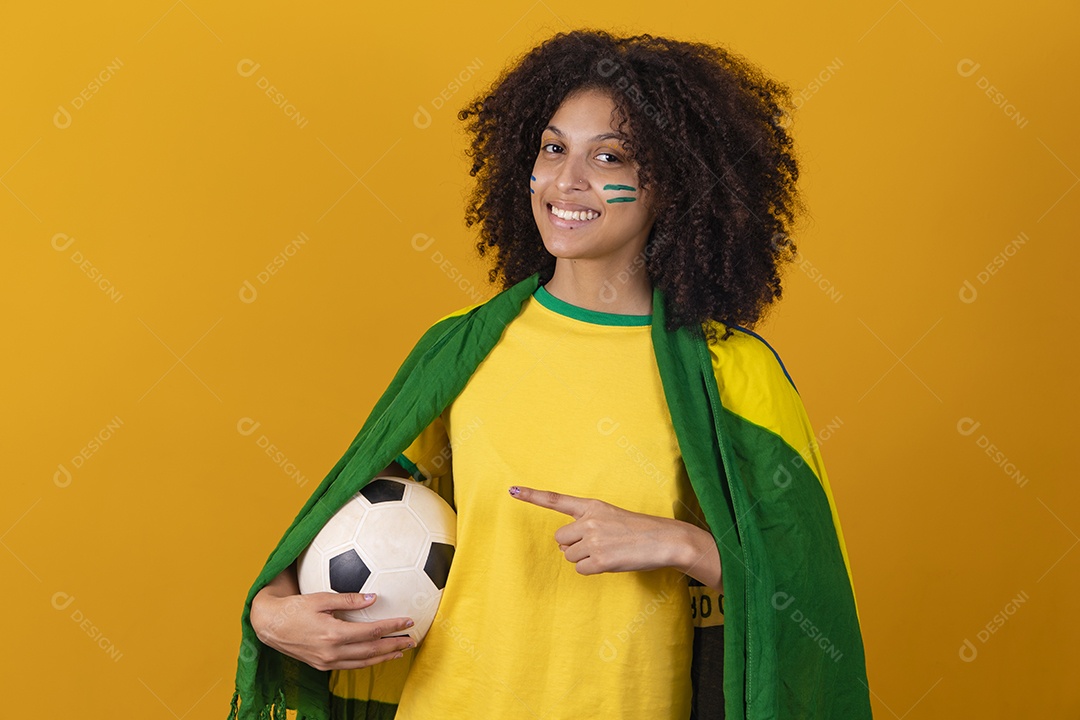 Mulher afro-brasileira vestindo camiseta do Brasil e segurando uma bola de futebol
