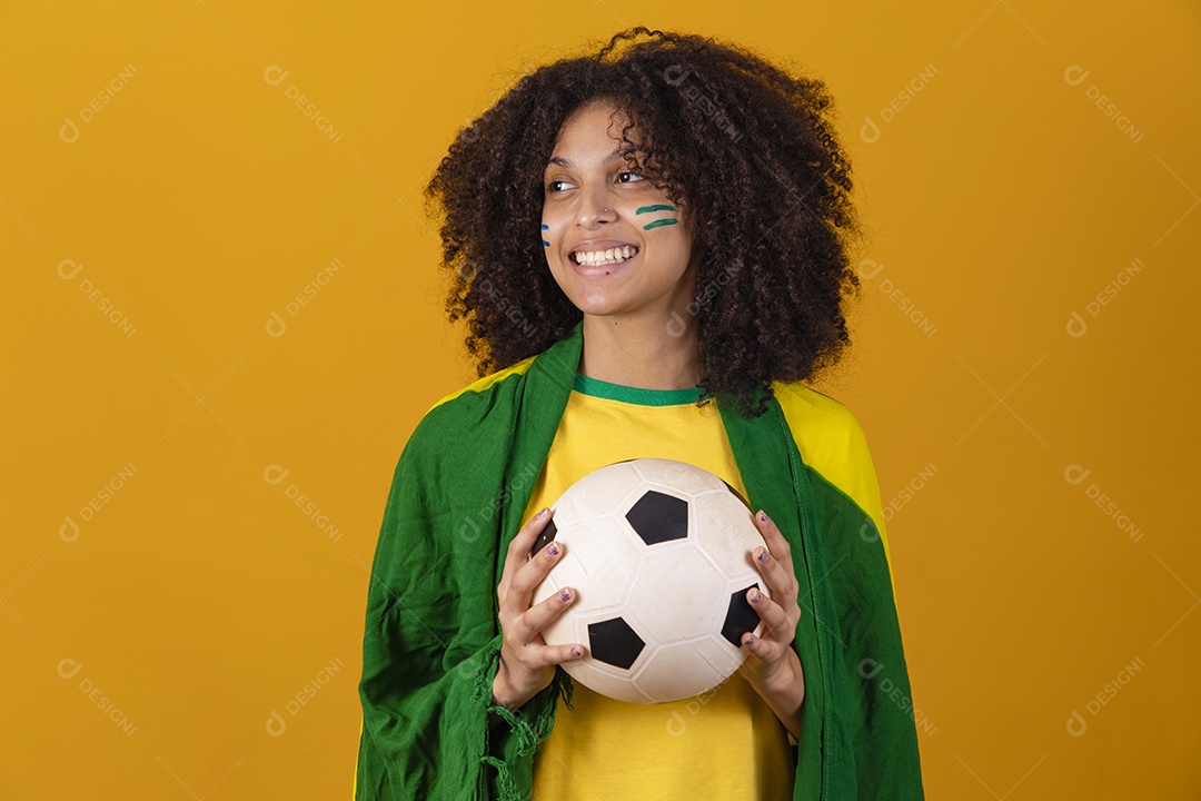 Mulher afro-brasileira vestindo camiseta do Brasil e segurando uma bola de futebol