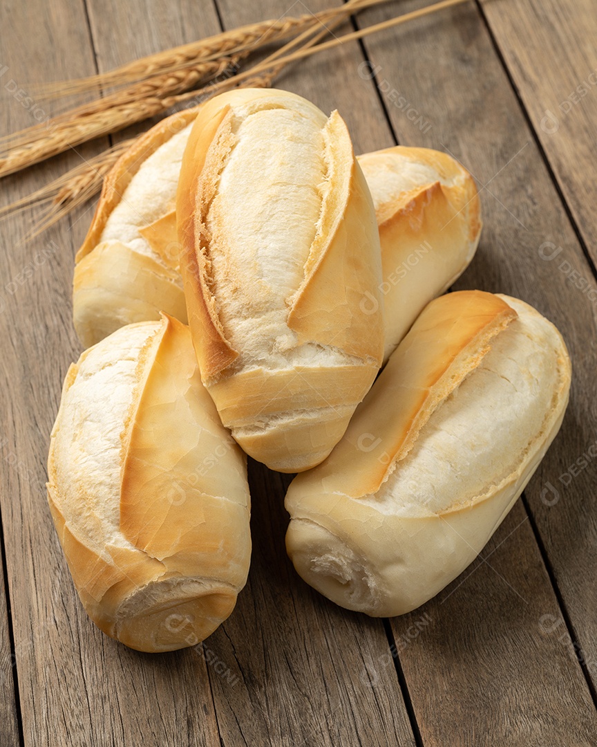 Pão francês integral, pão de sal ou pistolet em uma tigela sobre a mesa de madeira.