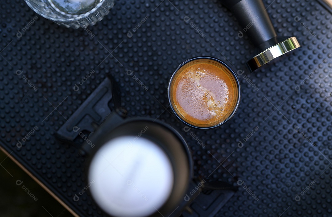 Foto de close-up do barista segurando a xícara de café mostrando crema, café lento, vista superior com foco no café.
