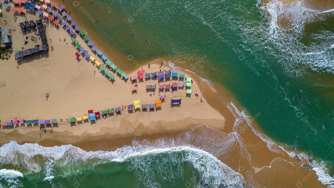 Vista aérea da praia de Caraiva, Porto Seguro, Bahia, Brasil. Barracas de praia coloridas, mar e rio.