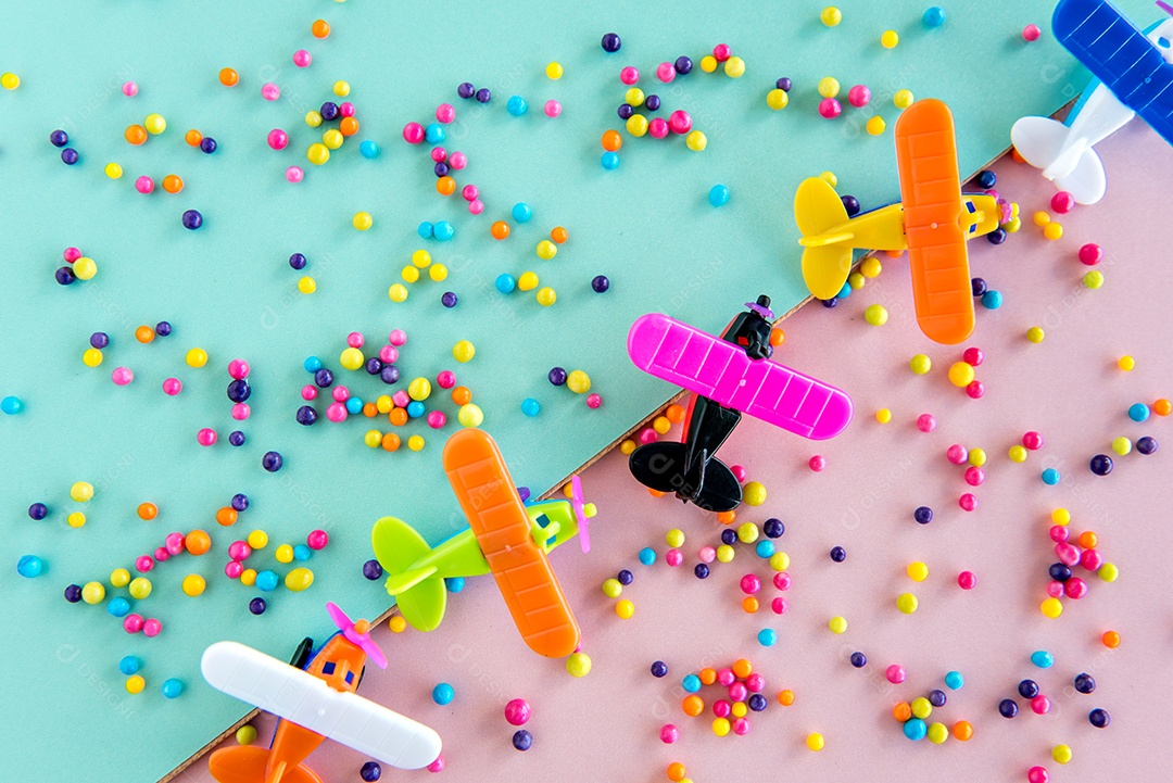 brinquedos de doces de plástico e avião em fundo verde e rosa