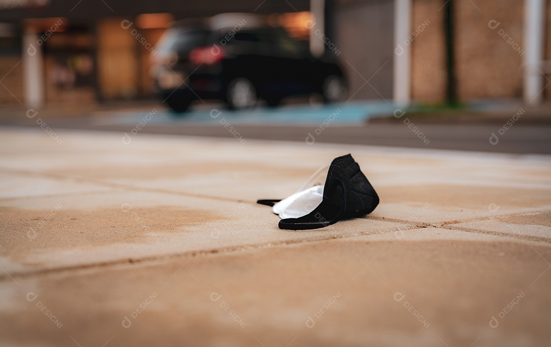 Descarte de máscara facial médica usada no chão do carro borrado no estacionamento e prédio na cidade.