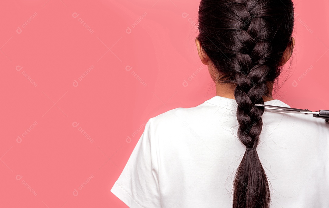 Vista traseira de uma mulher asiática com penteado trançado cortando com uma tesoura para doar a pacientes com câncer