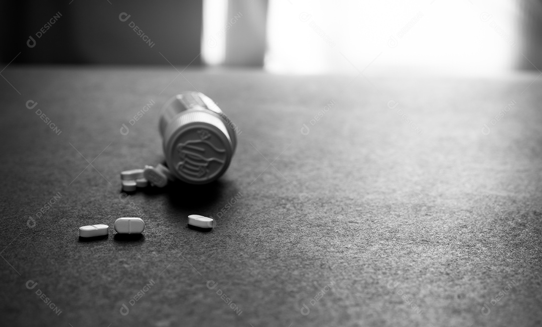 Comprimidos de comprimidos brancos e frasco de comprimidos de plástico azul no chão escuro.