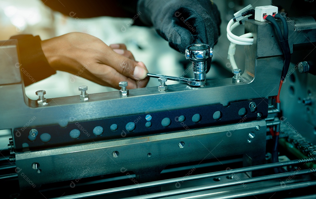 Mão de técnico mecânico consertando máquinas industriais na fábrica.