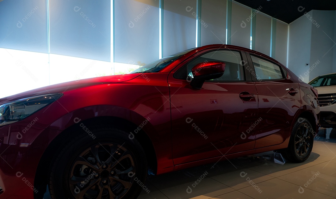 Carro brilhante vermelho estacionado no showroom moderno de luxo.