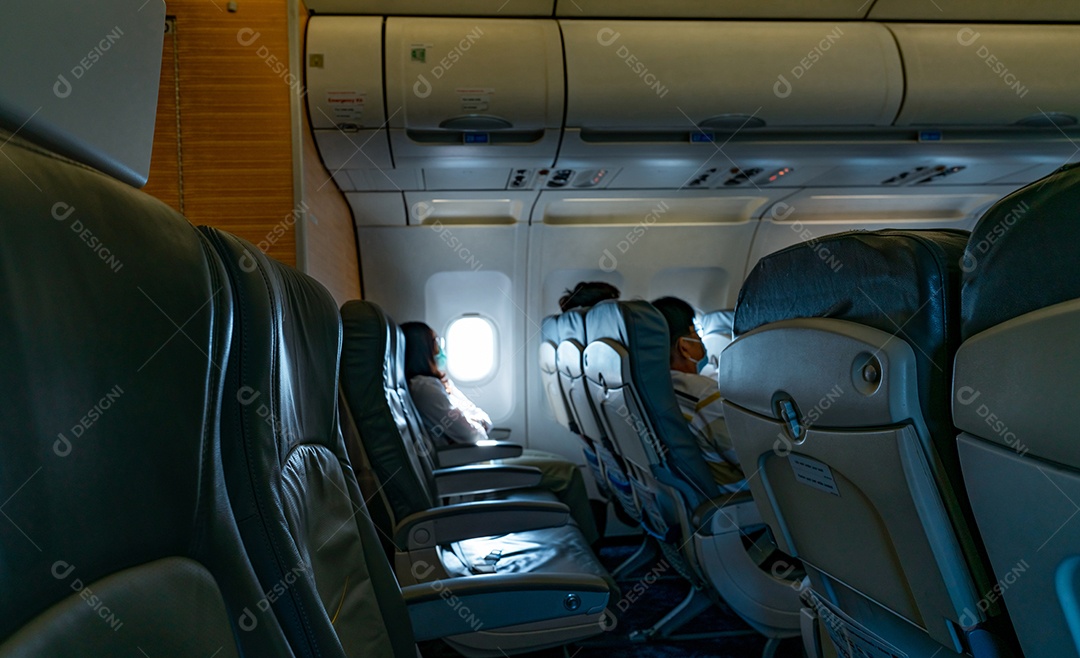 Os asiáticos desfocados usam máscara facial e sentam-se no banco do passageiro do avião