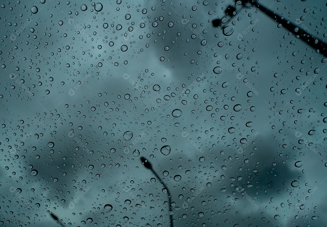 Pingos de chuva em vidro transparente contra borrão céu tempestuoso escuro