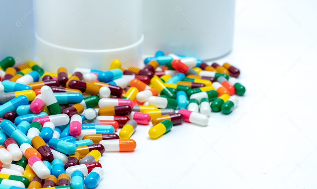 Comprimidos de cápsulas coloridas perto de frasco de droga de plástico.