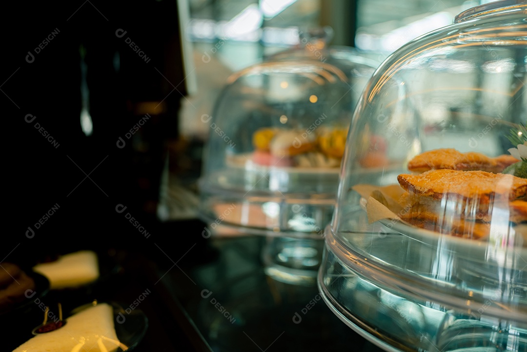 Pastelaria em exibição de suporte de vidro de bolo com cúpula de cobertura em cafeteria ou padaria.