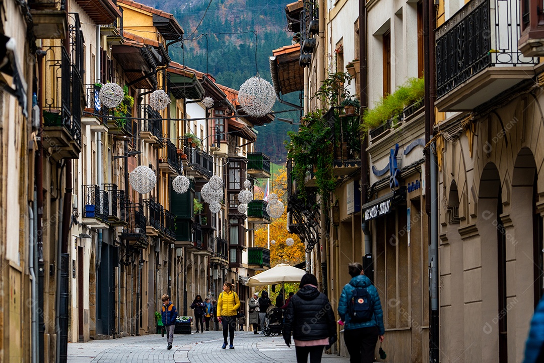 Pessoas andando na rua entre prédios antigos na Espanha.
