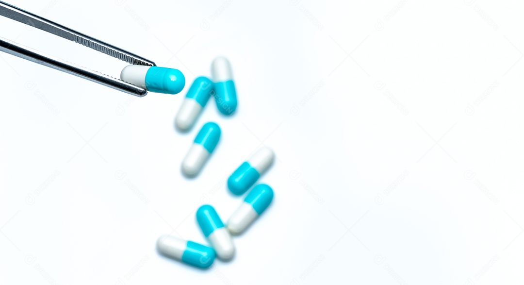 O fórceps escolhe a cápsula branco-azul do grupo de comprimidos da cápsula.