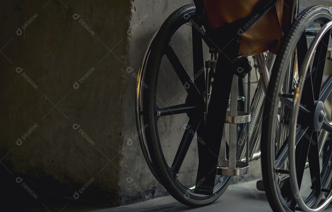 Cadeira de rodas dobrada ao lado da parede.