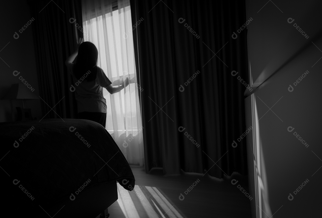 Vista traseira da mulher segurando a cortina e olhando para fora da janela de vidro
