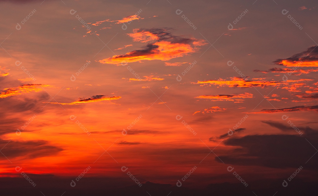 O céu e as nuvens vermelhos e alaranjados dramáticos abstraem o fundo