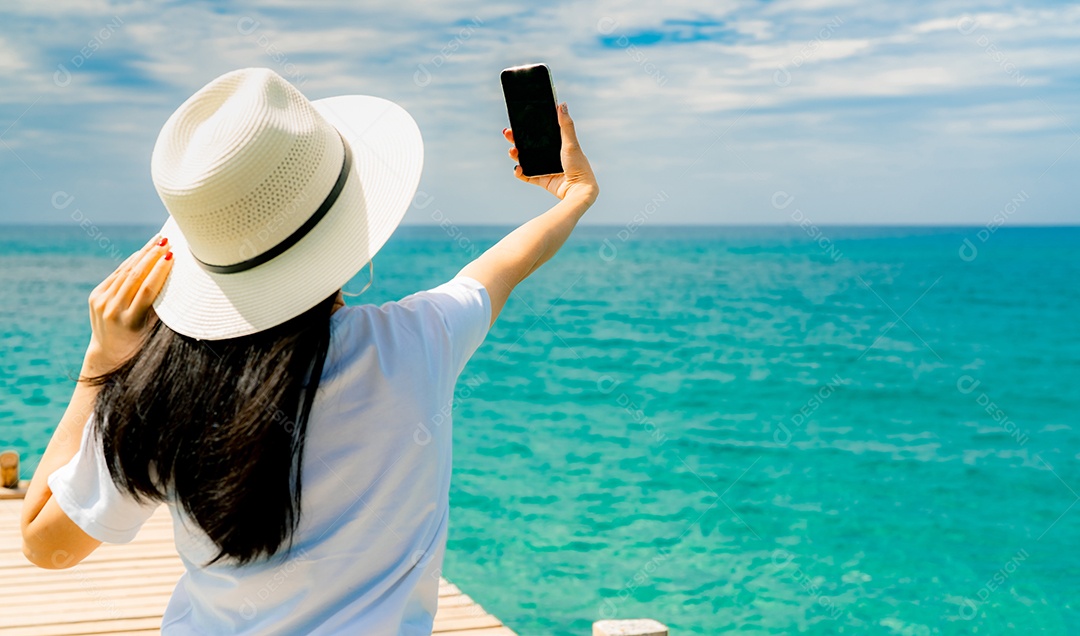 A jovem asiática usa chapéu de palha em estilo casual, usa smartphone