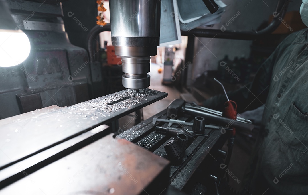 Fresadora trabalhando perto de trabalhador com máscara de proteção.