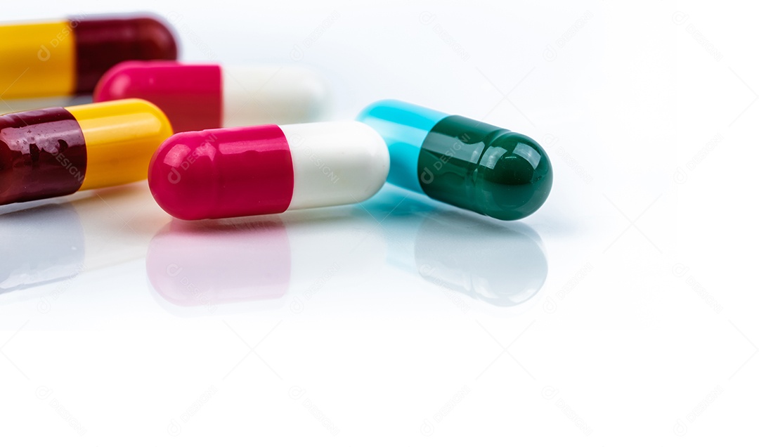 Comprimidos coloridos da cápsula do antibiótico no fundo branco. farmacêutico